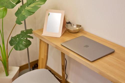 a laptop on a wooden table next to a plant at アーモンド石垣 in Tunugusuku