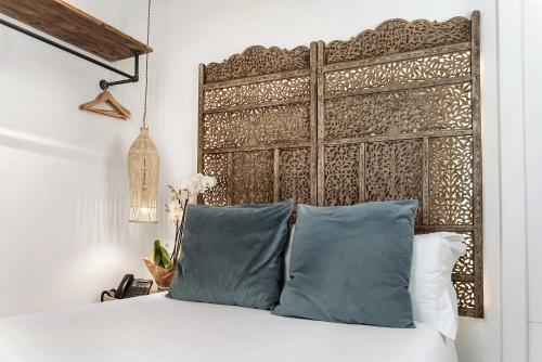 a bed with blue pillows and a wooden headboard at Hotel La Casa de Los Mosaicos by Maxi Hoteles in Granada