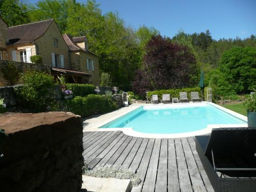 une piscine dans une cour avec des chaises et une maison dans l'établissement Les Cyprès du Brel, à Le Mas