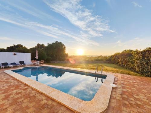 a swimming pool with a sunset in the background at Villa Nuralux - Vistas Espectaculares, Piscina Privada y BBQ in Sant Climent