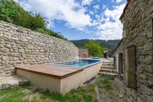 - une piscine avec une terrasse en bois à côté d'un bâtiment en pierre dans l'établissement La Villa du bonheur, à Puy-Saint-Martin