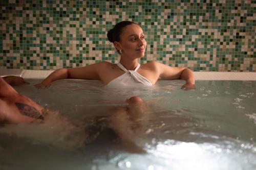 a woman sitting in a bath tub at Hi Hotels Torbole - Heated Outdoor Pool & Spa in Nago-Torbole