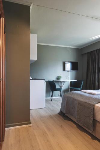 a hotel room with a bed and a kitchen and a table at Victoria hotell & apartments Fredrikstad in Fredrikstad