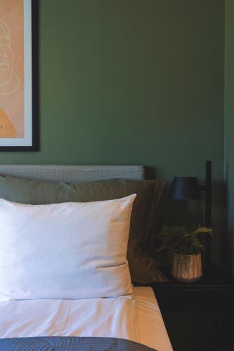 a bed with a white pillow and a green wall at Victoria hotell & apartments Fredrikstad in Fredrikstad