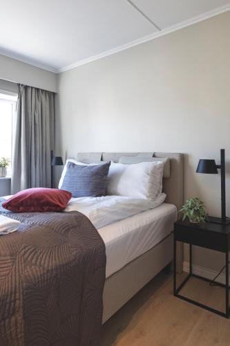 a bedroom with a bed with white sheets and a table at Victoria hotell & apartments Fredrikstad in Fredrikstad