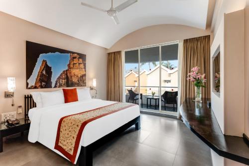 a bedroom with a large bed and a large window at Whispering Palms Beach Resort in Candolim