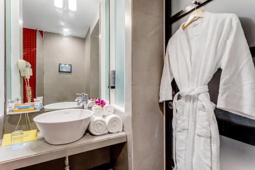 a bathroom with a sink and a white robe at Whispering Palms Beach Resort in Candolim