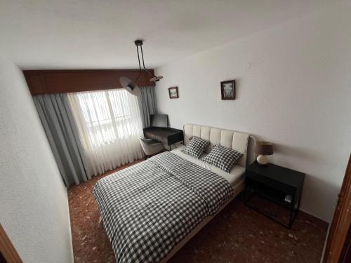 ein kleines Schlafzimmer mit einem Bett und einem Fenster in der Unterkunft Cullera-Apartment in Cullera