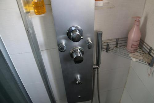 - une salle de bains avec une porte en métal et une bouteille sur une étagère dans l'établissement Les Capellans, port d'attache, à Saint Cyprien Plage