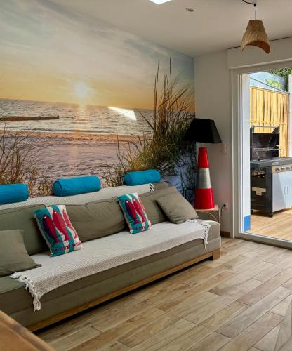 - un canapé dans une chambre avec une peinture représentant une plage dans l'établissement Maison avec terrasse, 10 couchages, à 200 m de la plage, à Berck-sur-Mer