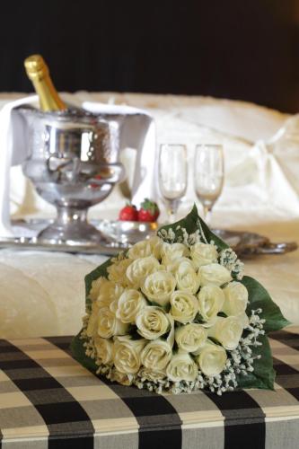 a bouquet of white roses on a table with wine glasses at Mati Hotel in Mati