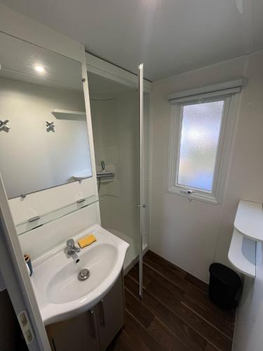une salle de bain blanche avec un lavabo et un miroir dans l'établissement Mobilhome 3ch N 145 - camping 4étoiles - Tout confort au calme, à Gastes