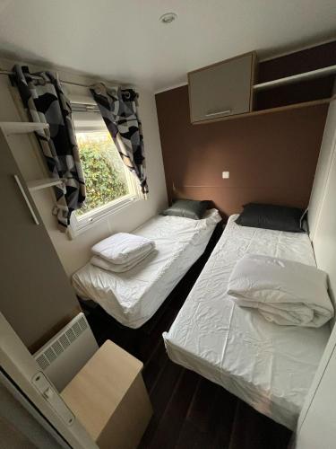 deux lits dans une petite pièce avec une fenêtre dans l'établissement Mobilhome 3ch N 145 - camping 4étoiles - Tout confort au calme, à Gastes