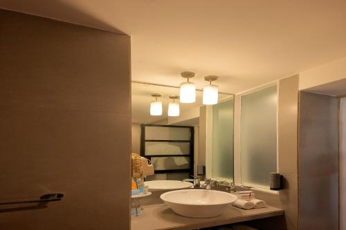 a bathroom with two sinks and two mirrors at Whispering Palms Beach Resort in Candolim