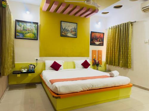 a bedroom with a bed with a yellow wall at Nilkanth Resort - Best Resort in Anand in Anand