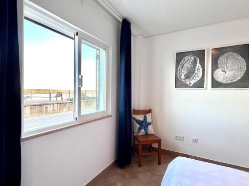 a bedroom with a large window and a chair at Refúgio da Ria By ALGARTUR in Cabanas de Tavira