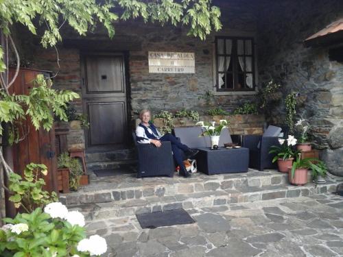 a woman sitting on a chair in front of a building at Casa Rural O Carreiro in Cedeira