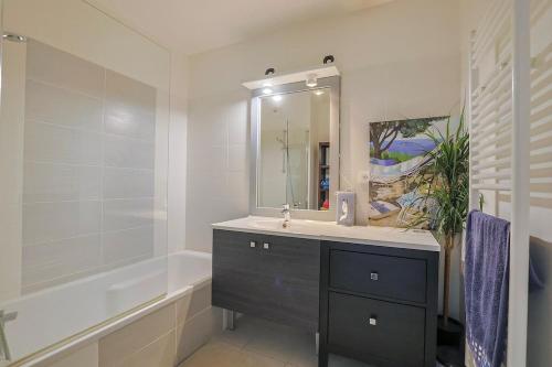 une salle de bain avec un lavabo, une baignoire et un miroir dans l'établissement Air-conditioned south-facing apartment, à Hyères