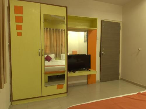 a room with a bedroom with a tv and a mirror at Nilkanth Resort - Best Resort in Anand in Anand