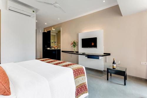 a bedroom with a bed and a tv on a wall at Whispering Palms Beach Resort in Candolim