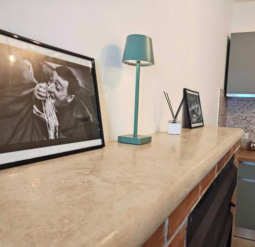 a table with a framed picture and a lamp on it at Casa Anna Cerasuolo - intera casa indipendente in borgo in Cerasuolo