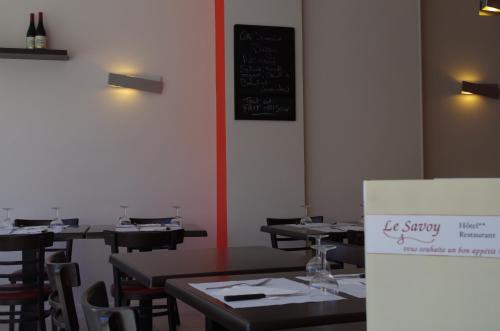 a dining room with tables and chairs and a chalkboard at The Originals City, Hôtel Le Savoy, Caen in Caen