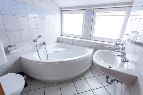 a white bathroom with a tub and a sink at U-Nautic Restaurant & Pension in Waren
