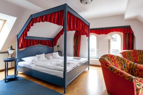 a bedroom with a canopy bed with red curtains at U-Nautic Restaurant & Pension in Waren