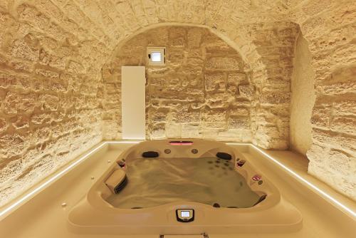 a bath tub in a room with a stone wall at Divine Couture - Suite Cambon in Carrières-sur-Seine