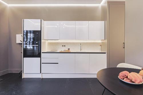 a kitchen with white cabinets and a black refrigerator at Divine Couture - Suite Cambon in Carrières-sur-Seine