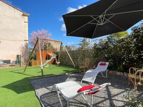 a patio with two chairs and an umbrella and a playground at Évasion ensoleillée avec jacuzzi à Cazedarnes in Cazedarnes