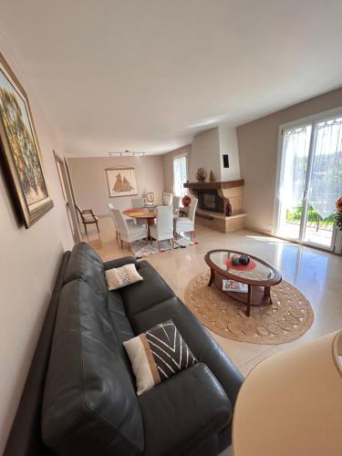 un salon avec un canapé en cuir noir et une table dans l'établissement Splendide Villa, grand jardin à 2 pas du Golf, à Levernois