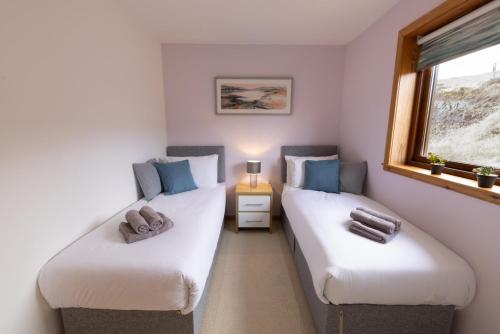 two twin beds in a room with a window at Botaira, Shetland Islands in Easter Quarff