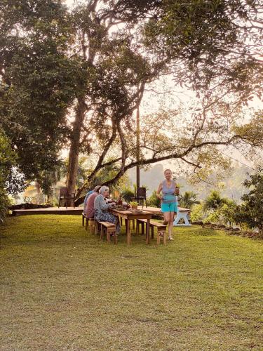 Un grupo de personas sentadas en una mesa de picnic en un parque. en Richiland Tea Estate Bungalow, en Deniyaya