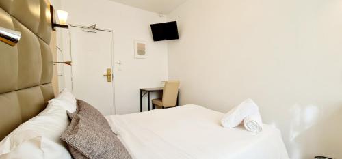 a small bedroom with a white bed and a table at Hotel de France 18 in Paris