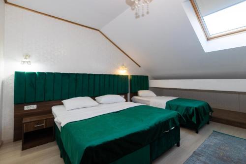 two beds in a room with green walls at Hotel Merty in Constanţa
