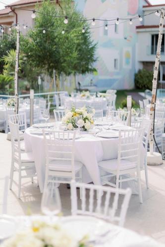 a white table with white chairs and tables with flowers at Nayino Resort Hotel in Mamaia Nord