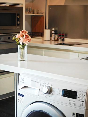a kitchen with a washing machine with a vase of flowers at City comfort appartment, Skytain Step 600 m, Erawan shrine in Bang Kapi