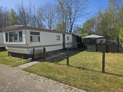 a mobile home with a fence in a yard at It wiide sicht in Earnewâld