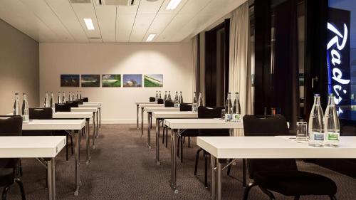 a room with white tables and chairs with bottles on them at Radisson Blu Hotel Zurich Airport in Kloten
