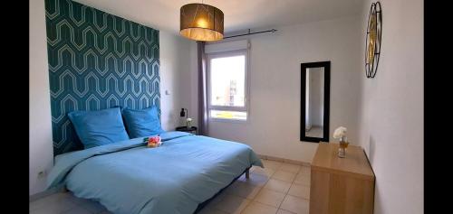une chambre avec un lit bleu et une fenêtre dans l'établissement Perle centre ville, à Saint-Priest