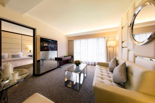 a living room with a couch and a mirror at Regal Kowloon Hotel in Hong Kong