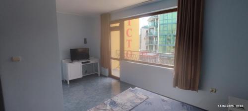 a living room with a window and a television at Vila Victoria Primorsko in Primorsko