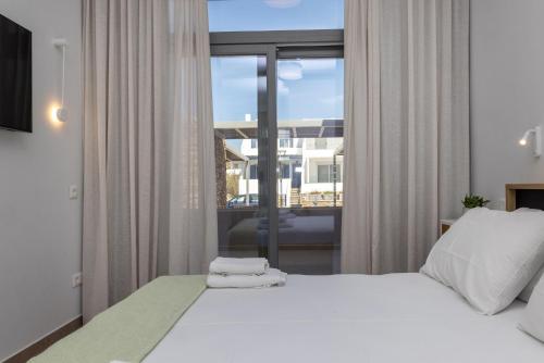 a bedroom with a white bed and a large window at Blu in Tinos Town