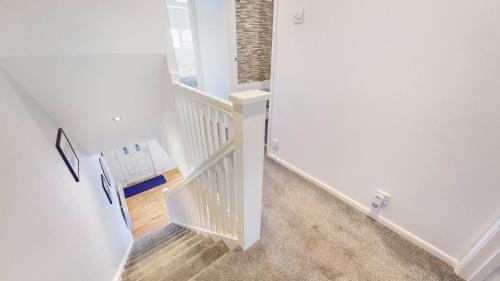 a hallway with a staircase with white walls and wood floors at Mavisbank Gardens in Glasgow