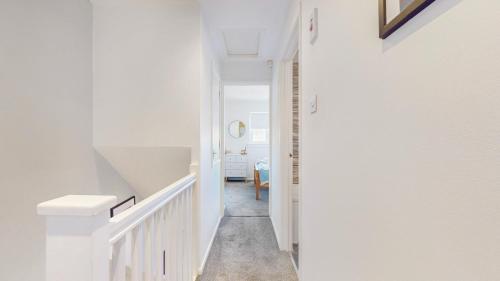 a hallway with white walls and a white staircase at Mavisbank Gardens in Glasgow