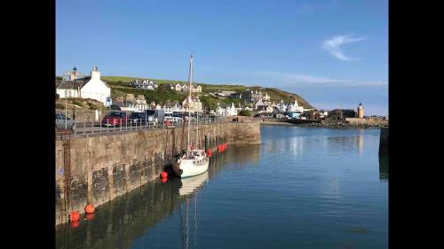 a boat is docked in a river next to a wall at Cosy Holiday Home Portpatrick in Portpatrick