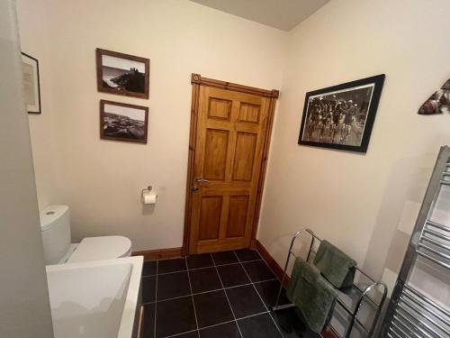 a bathroom with a toilet and a wooden door at Cosy Holiday Home Portpatrick in Portpatrick