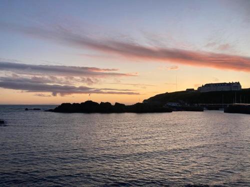 a sunset over a body of water with an island at Cosy Holiday Home Portpatrick in Portpatrick