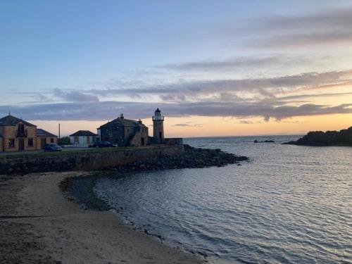 a lighthouse on the shore of a body of water at Cosy Holiday Home Portpatrick in Portpatrick